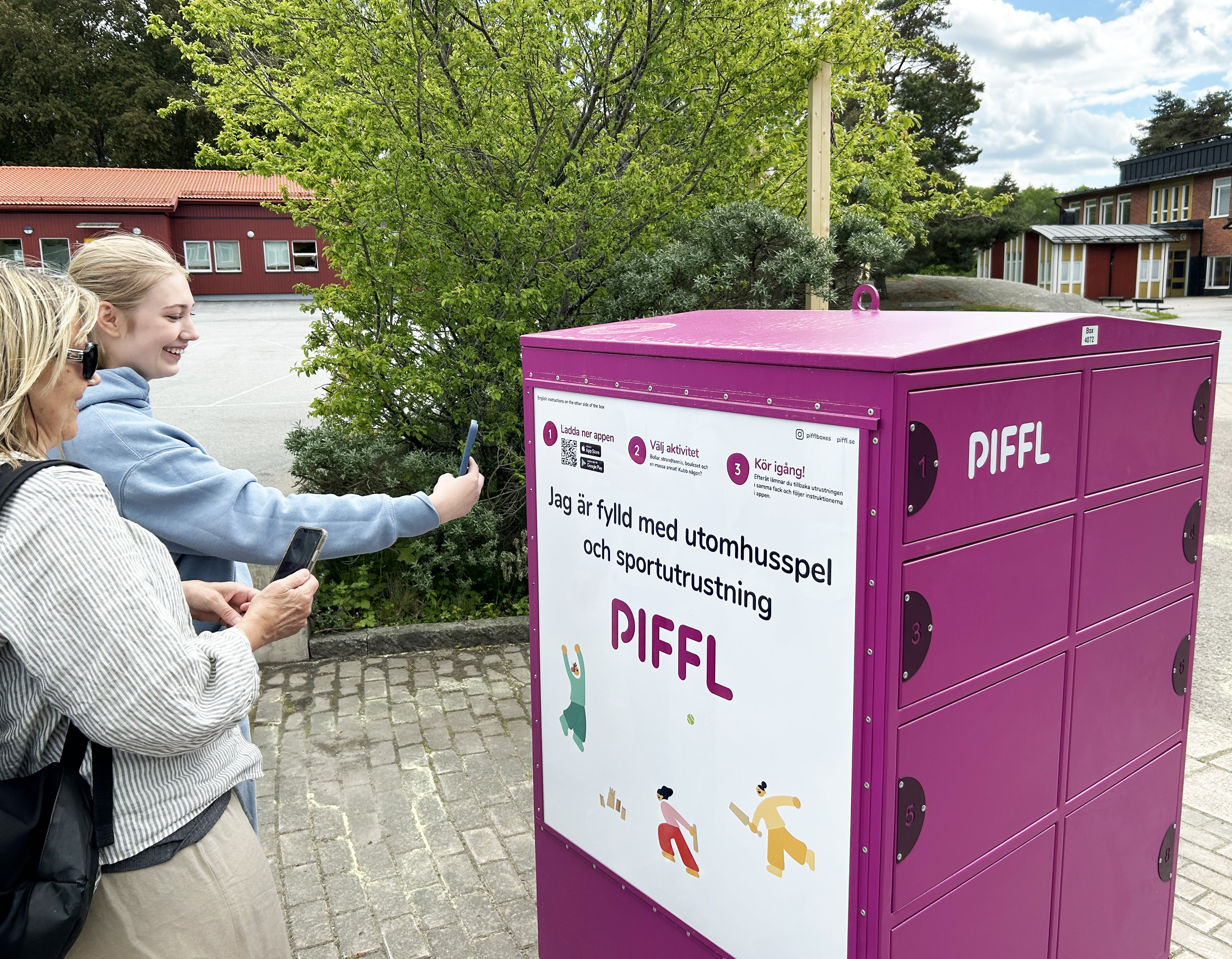 Två personer scannar en QR-kod med mobiltelefon på en aktivitetsbox 