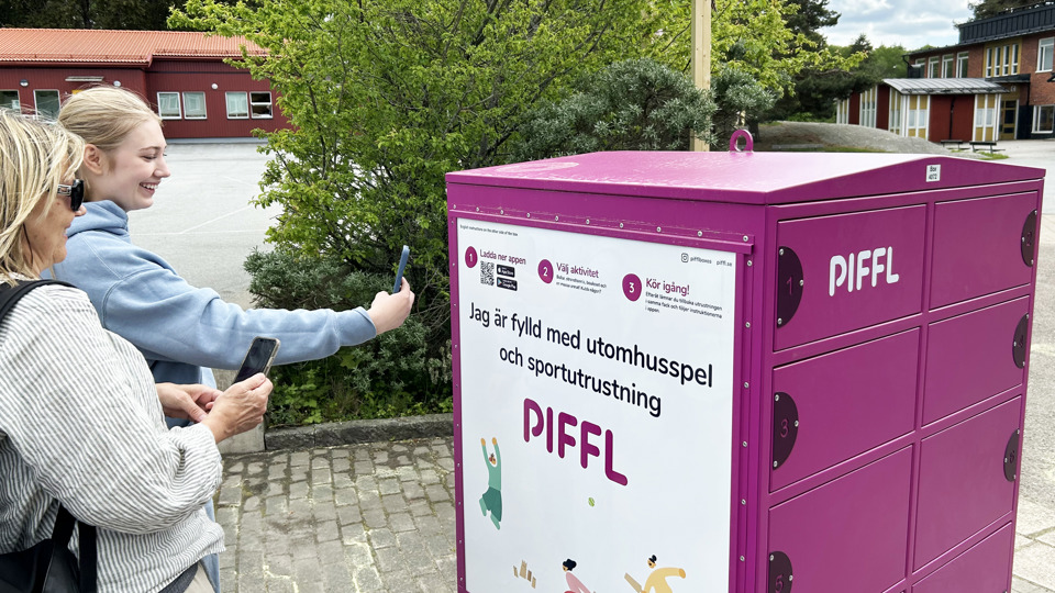 Två personer scannar en QR-kod med mobiltelefon på en aktivitetsbox 
