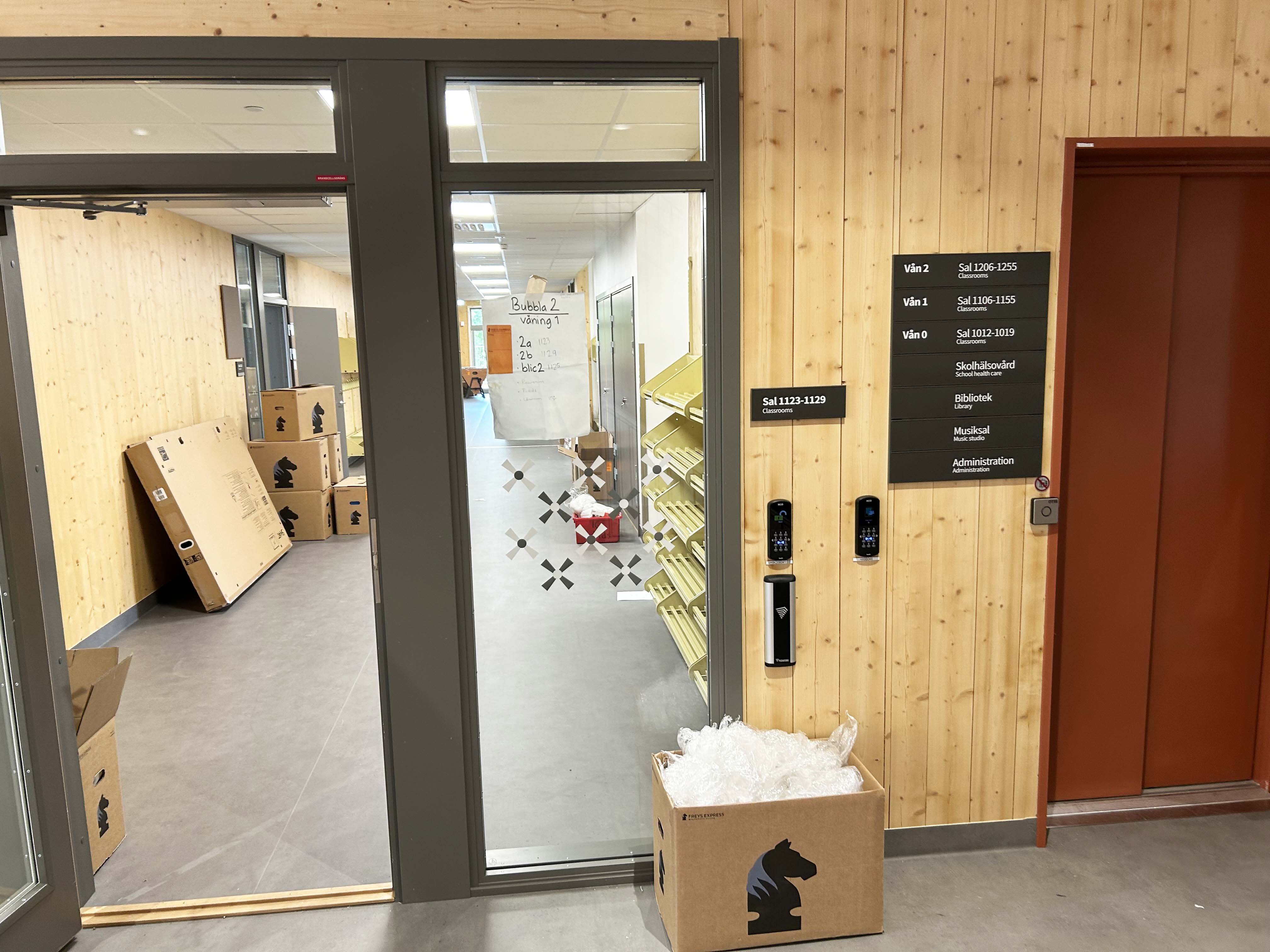 Flyttlådor vid en korridor i en nybyggd skola.