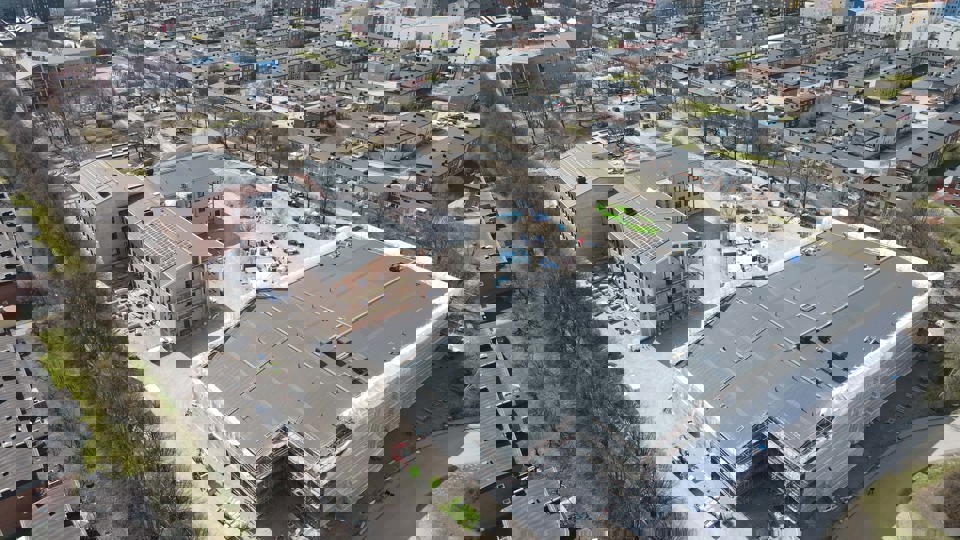 Flygbild över byggplats med omgivande bebyggelse