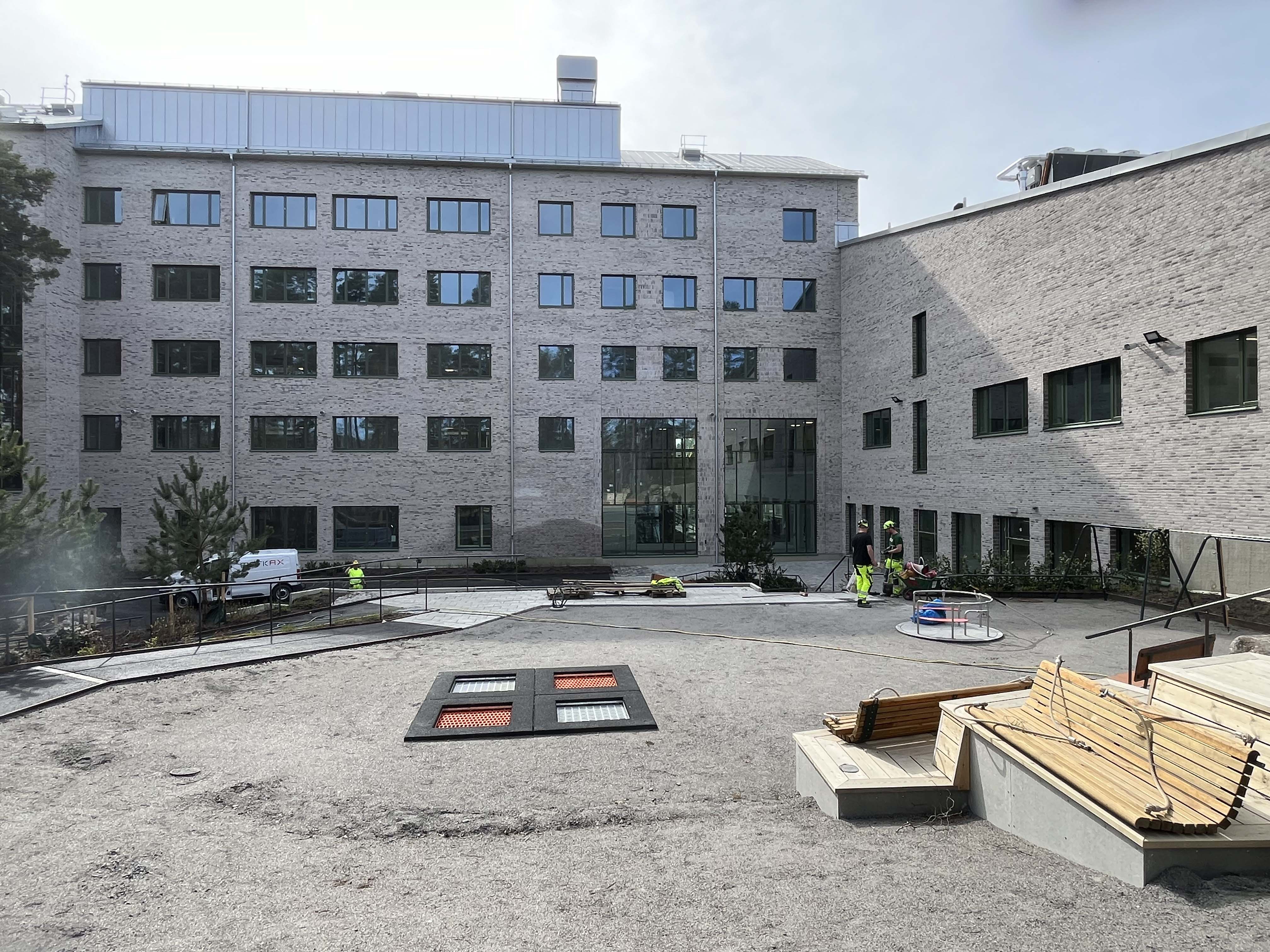 Fasaden på en skolbyggnad med skolgård i förgrunden.