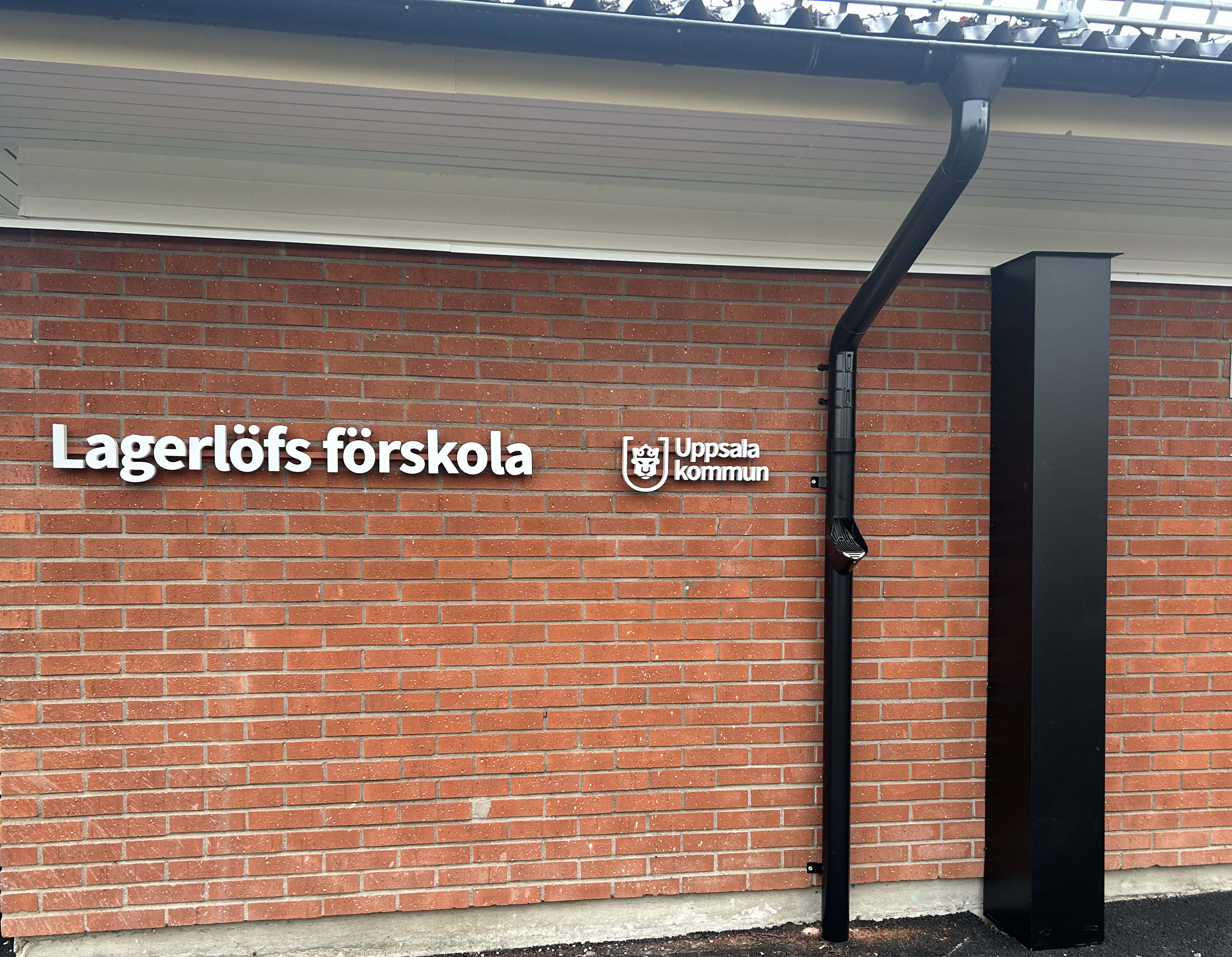 Brun tegelvägg med förskoleskylt.