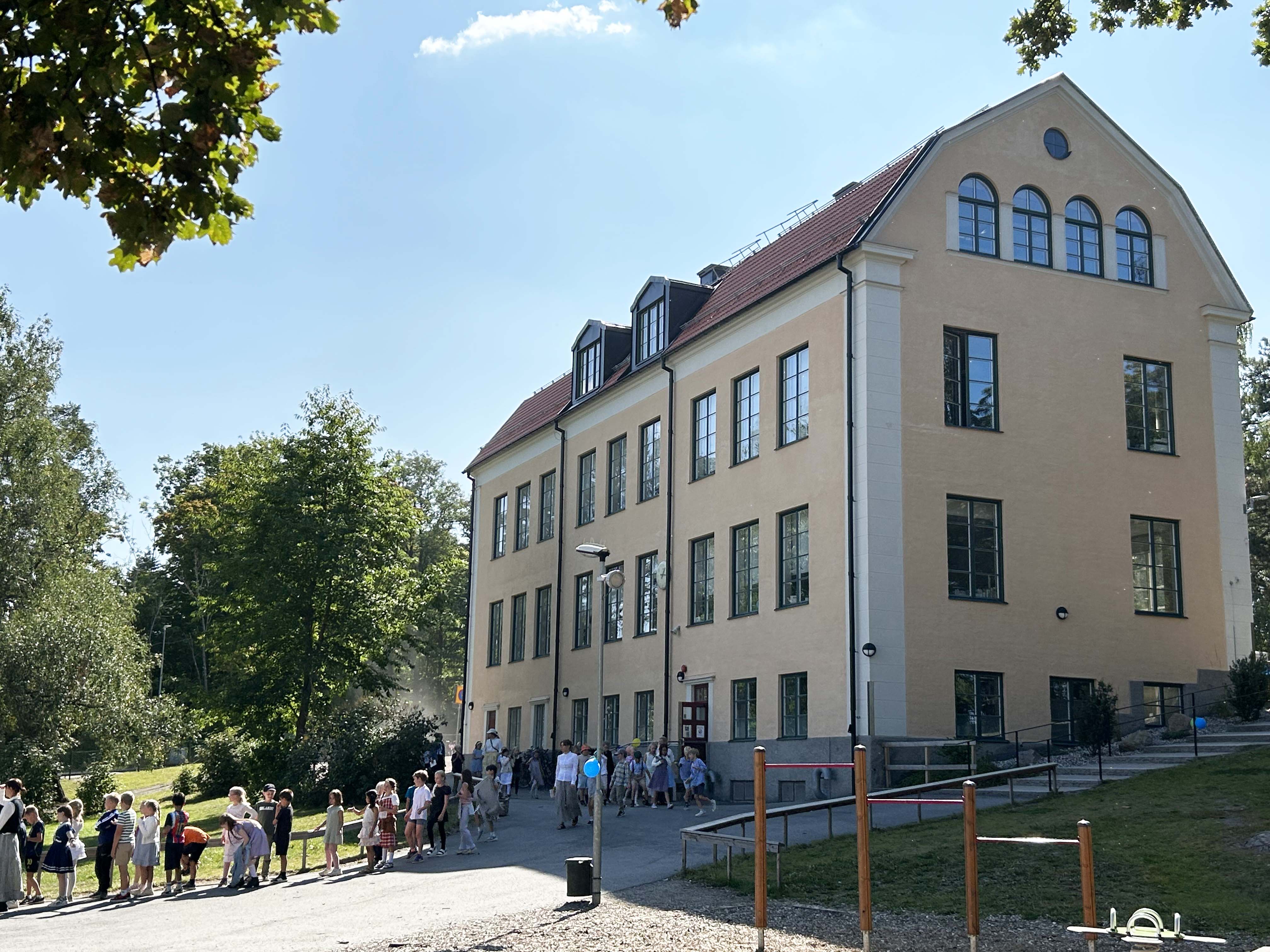Skolbyggnad med barn som går på led