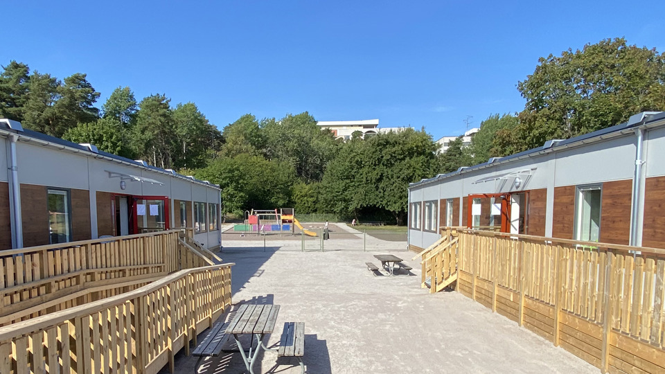 Modulförskola med rutschkana och klätterställningar i bakgrunden.