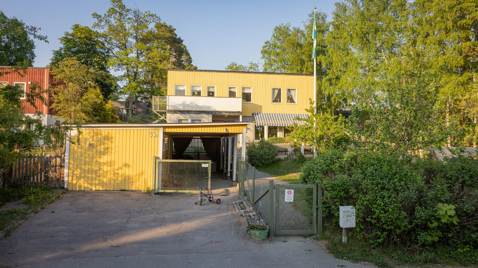 Förskolebyggnad i gult trä med grön gård