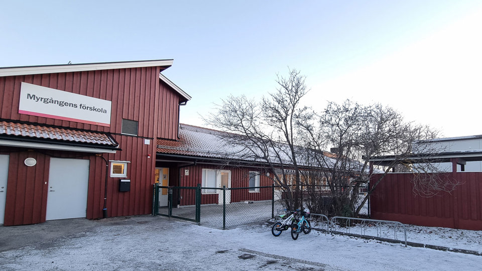 Röd förskolebyggnad med snö i förgrunden.