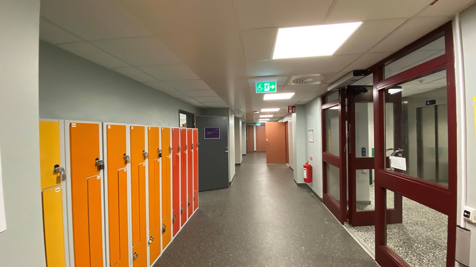 Korridor i skola kantad av färgglada förvaringsskåp  