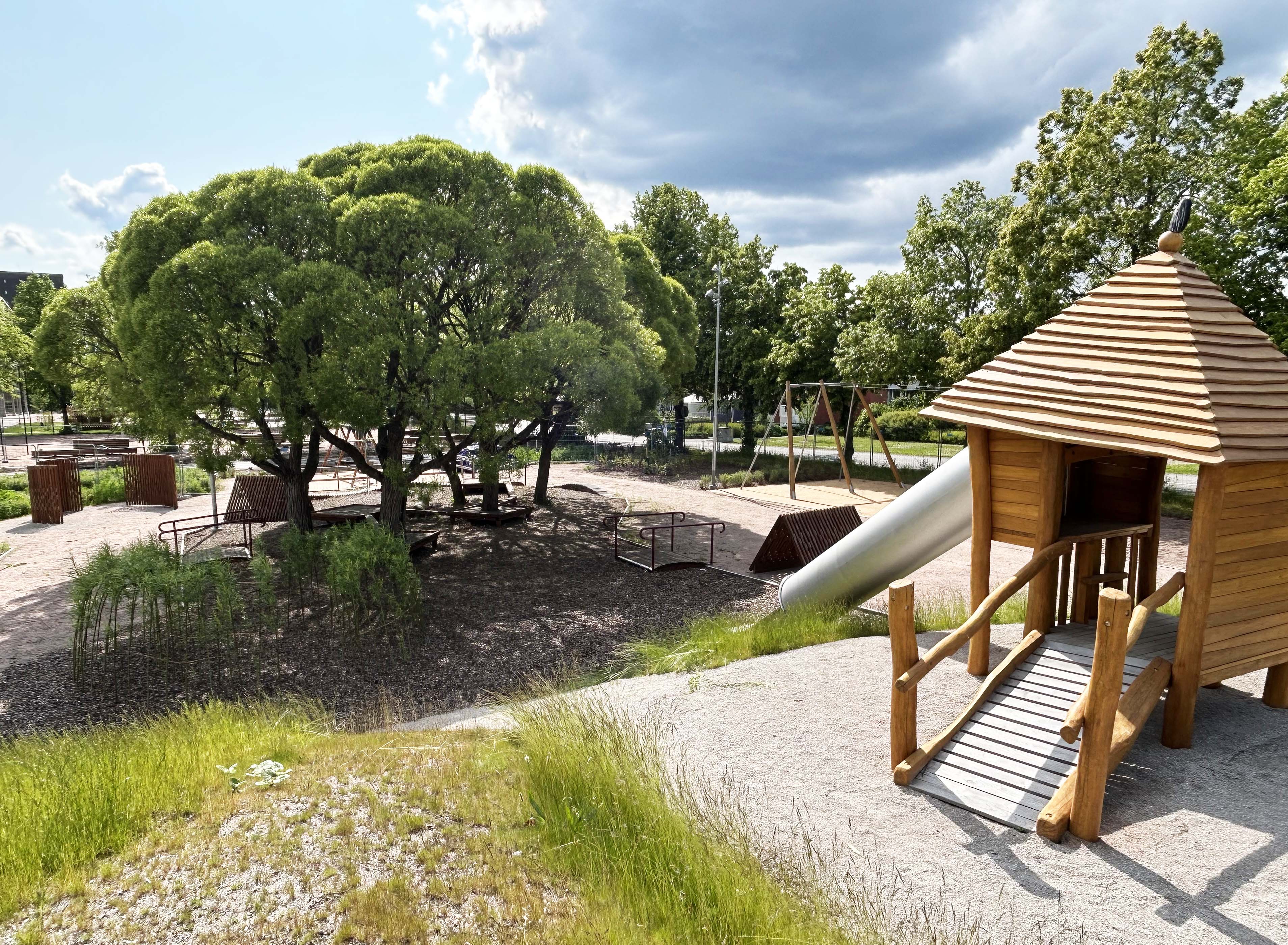 Nybyggd skolgård med lekutrustning i trä och grönytor.