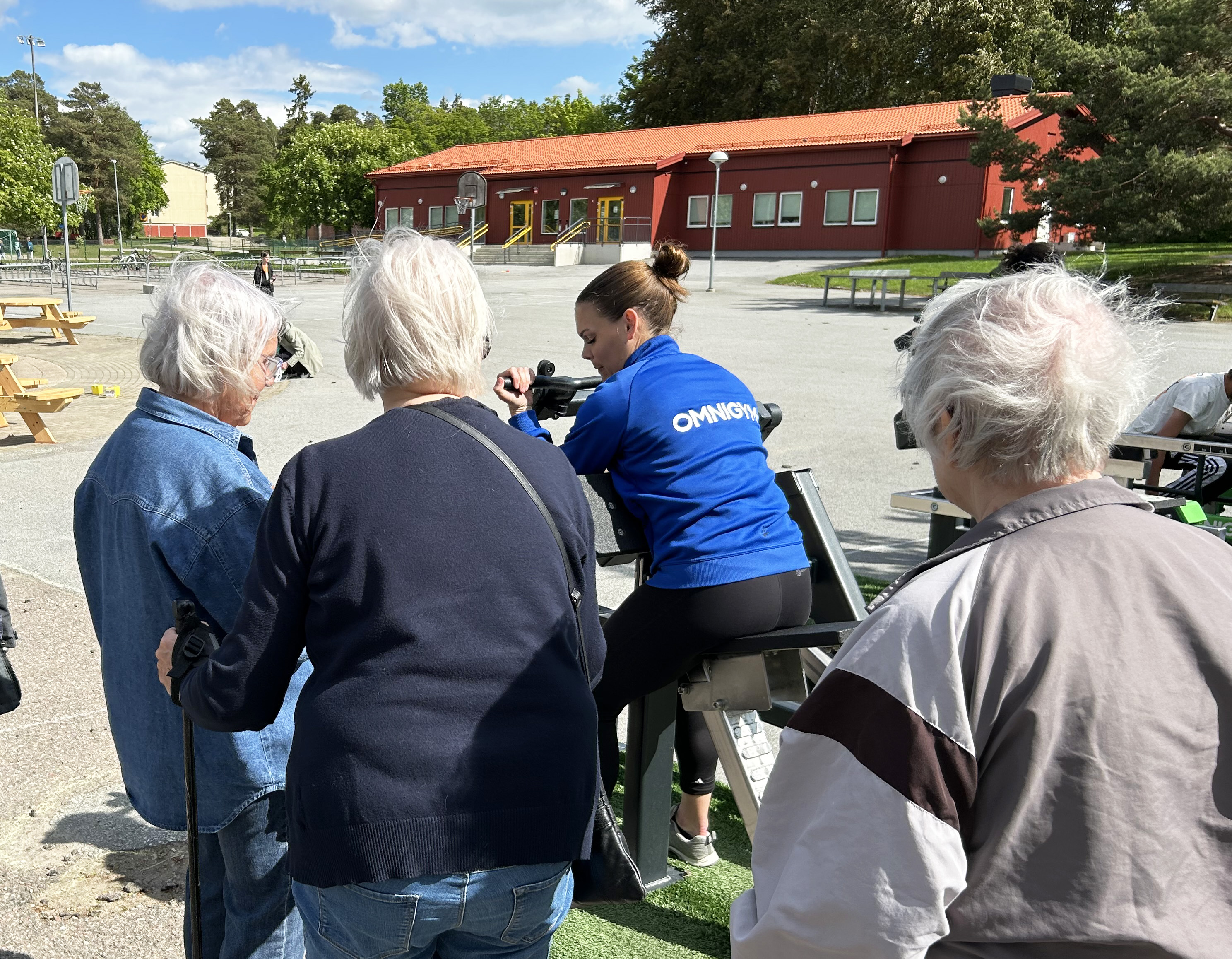 En kvinna ger instruktioner till pensionärer vid ett utegym.