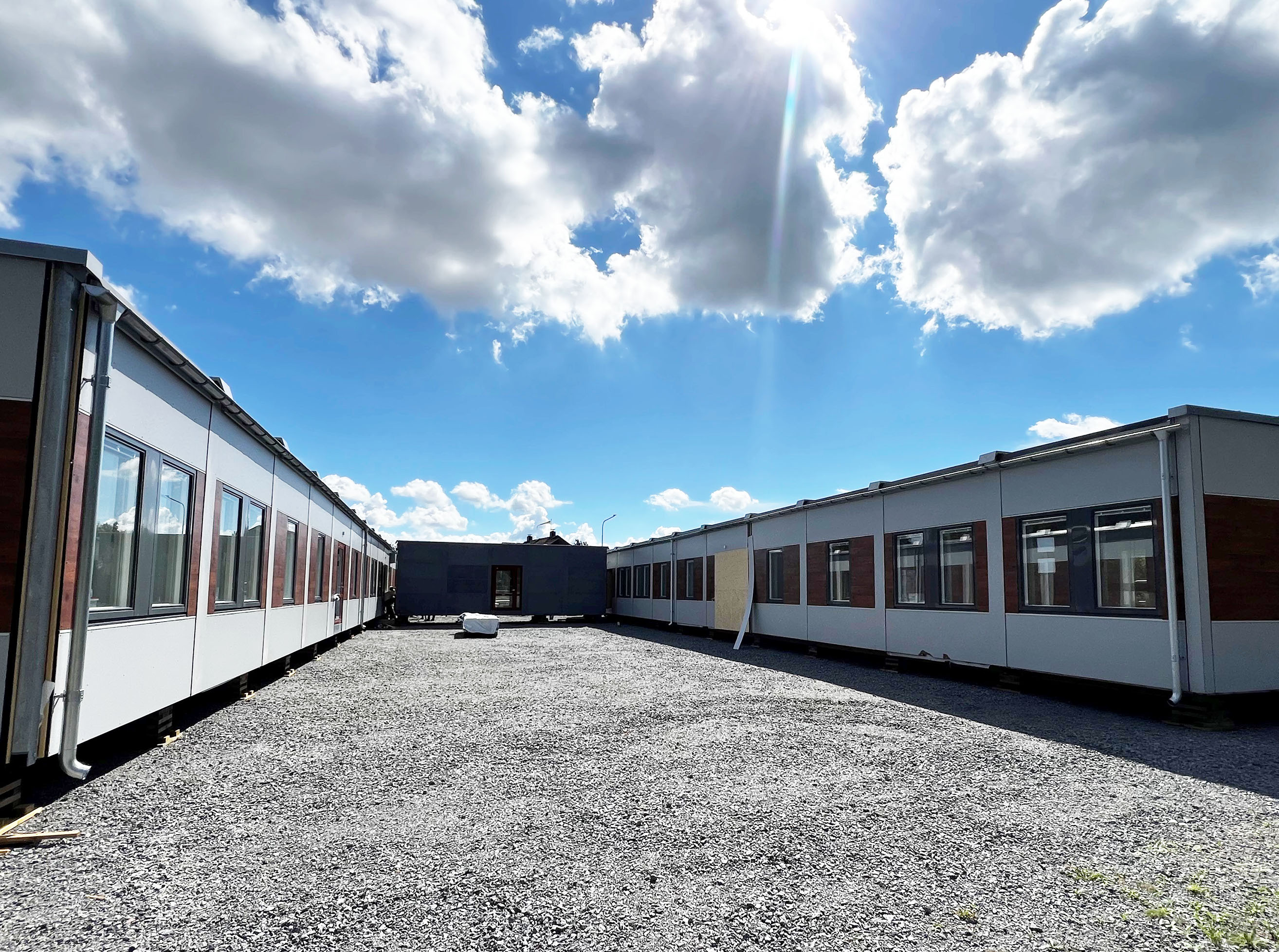 Nya förskolemoduler på grusyta med blå himmel i bakgrunden.