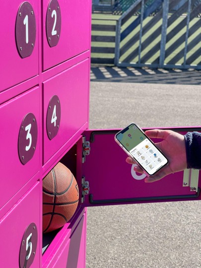 Hand med telefon som öppnar ett rosa skåp med basketboll i.