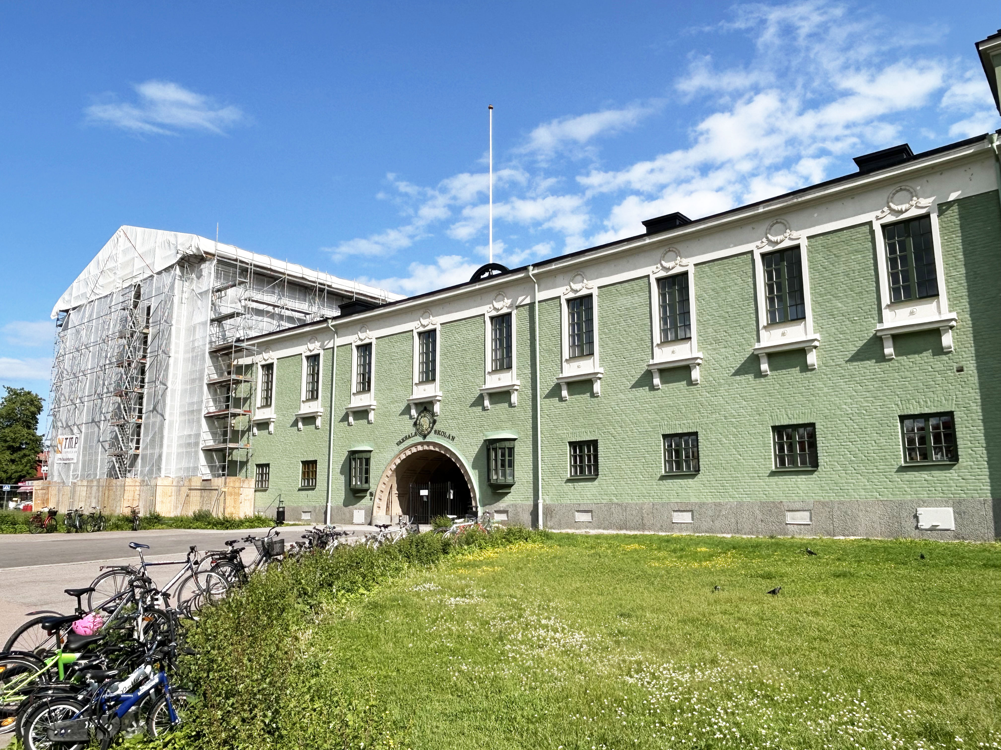 En gammal, fin skola i grön färg som fasadrenoveras.