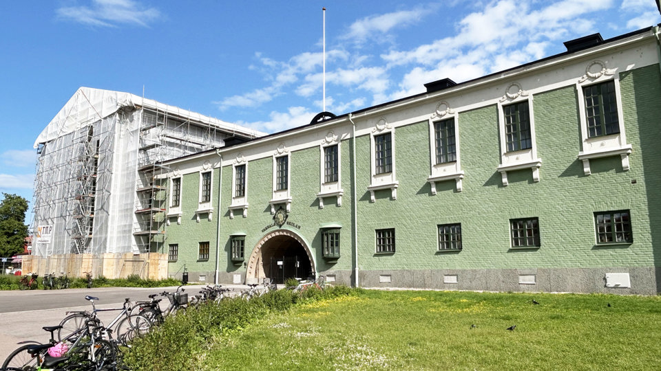 En gammal, fin skola i grön färg som fasadrenoveras.