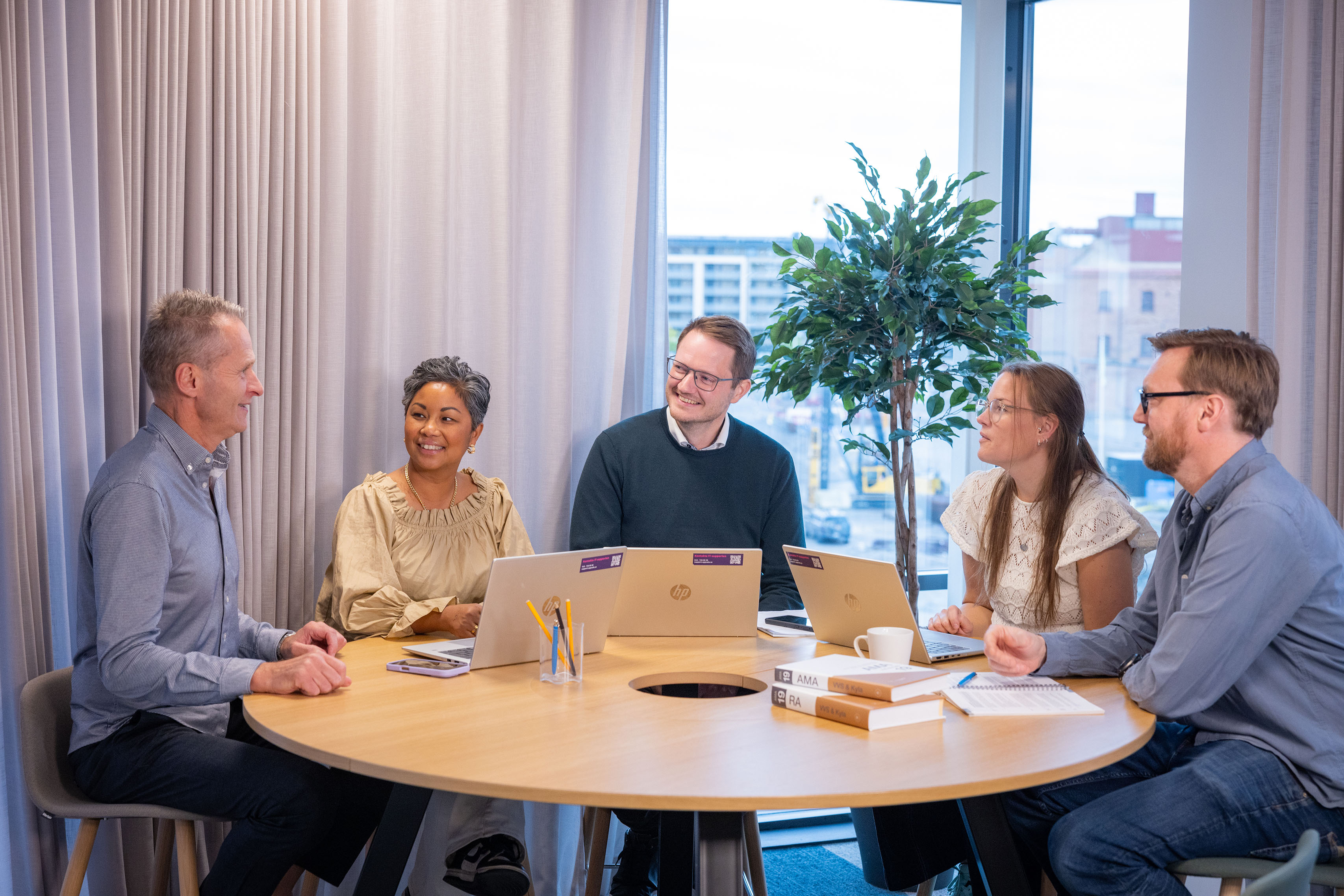 Fem kollegor arbetar med dator vid ett bord