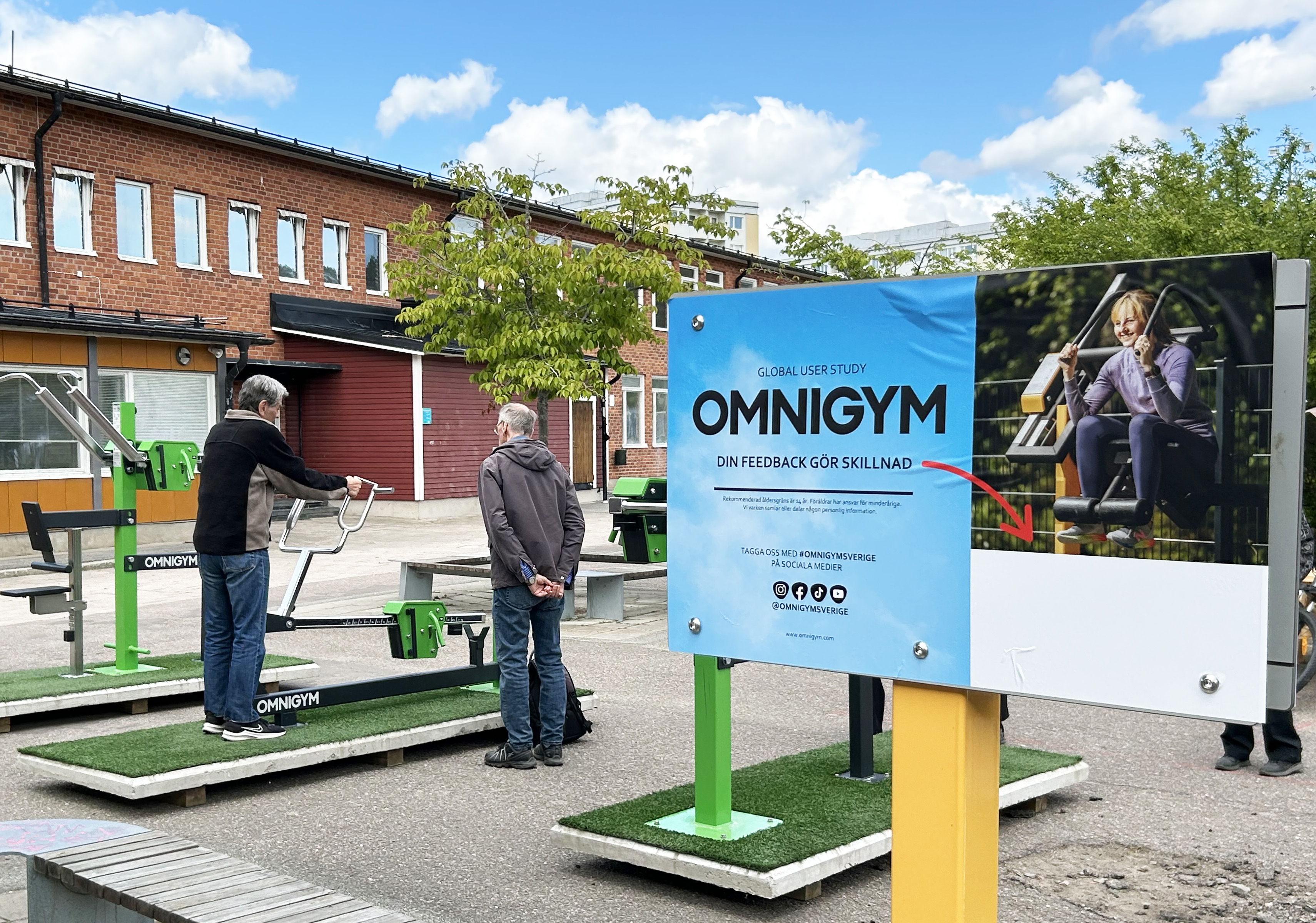 Två pensionärer testar ett utegym på en skolgård.
