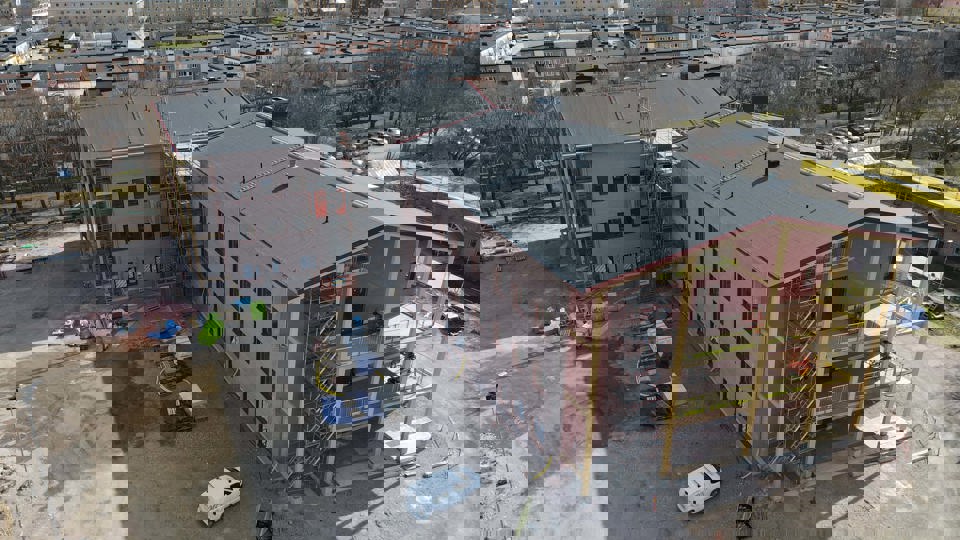 Flygbild över byggplats med omgivande bebyggelse