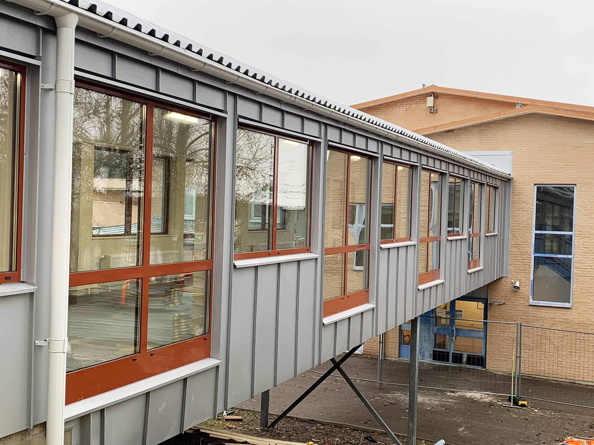 Nyrenoverad skolbyggnad med glaskorridor.