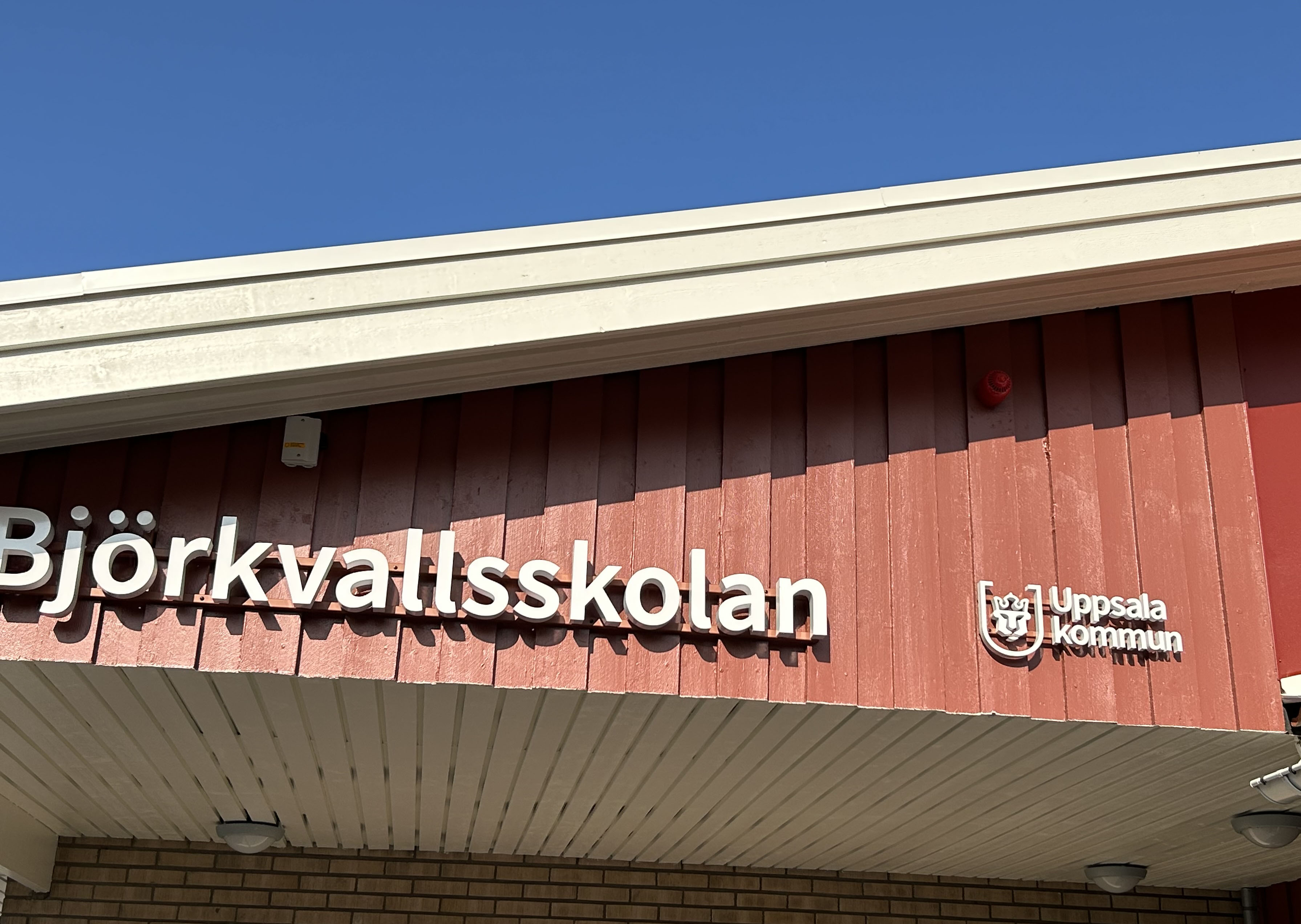 Fasadskylt på röd träfasadför en nyrenoverad skola.