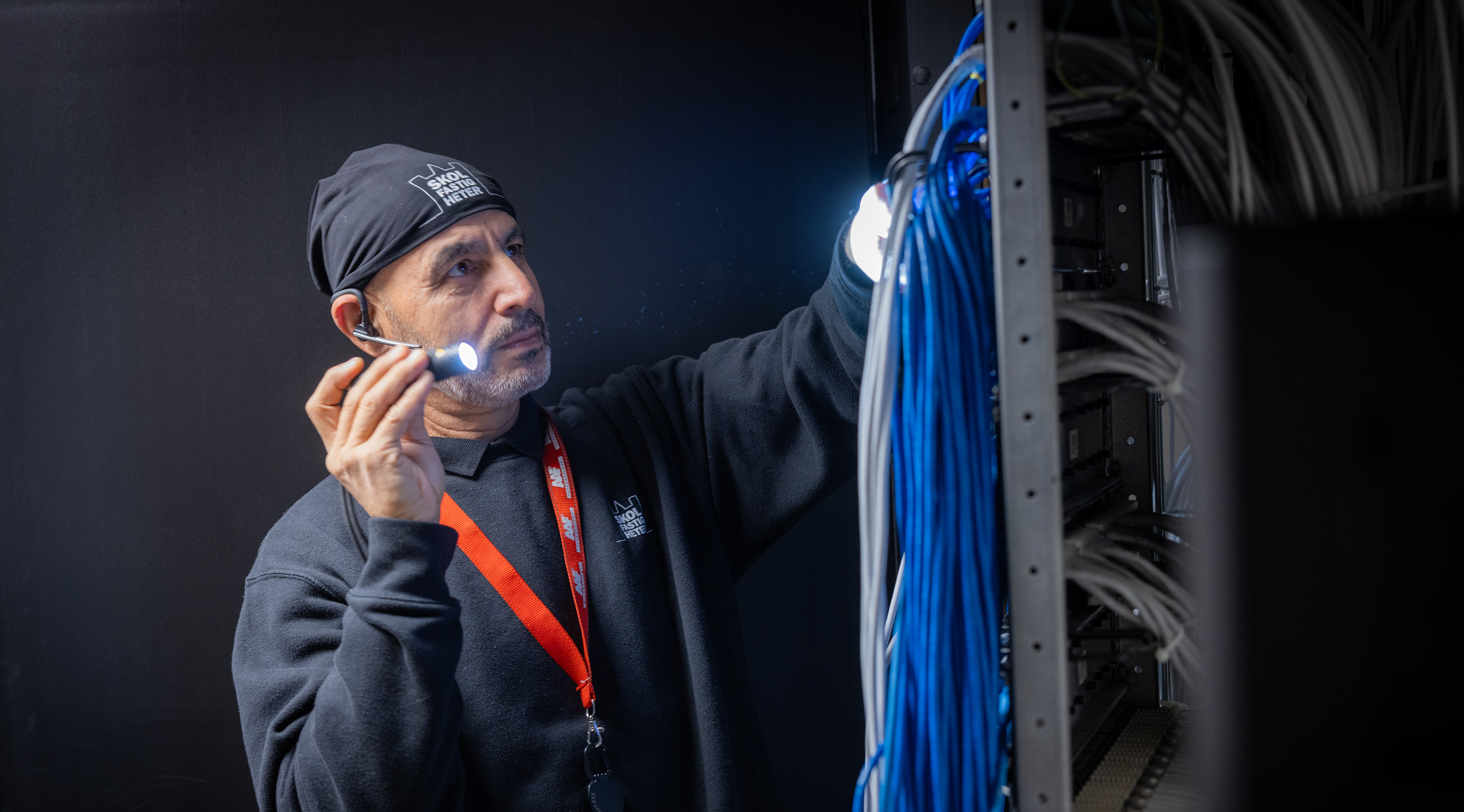 Drifttekniker med ficklampa vid elcentral